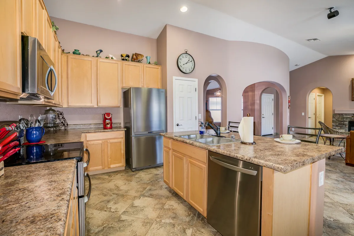 A modern kitchen island with stainless steel appliances and ample counter space, extending into a dining area. The scene is set for both cooking and group dining, with natural light brightening the area and subtle decorative touches enhancing the homey feel.
