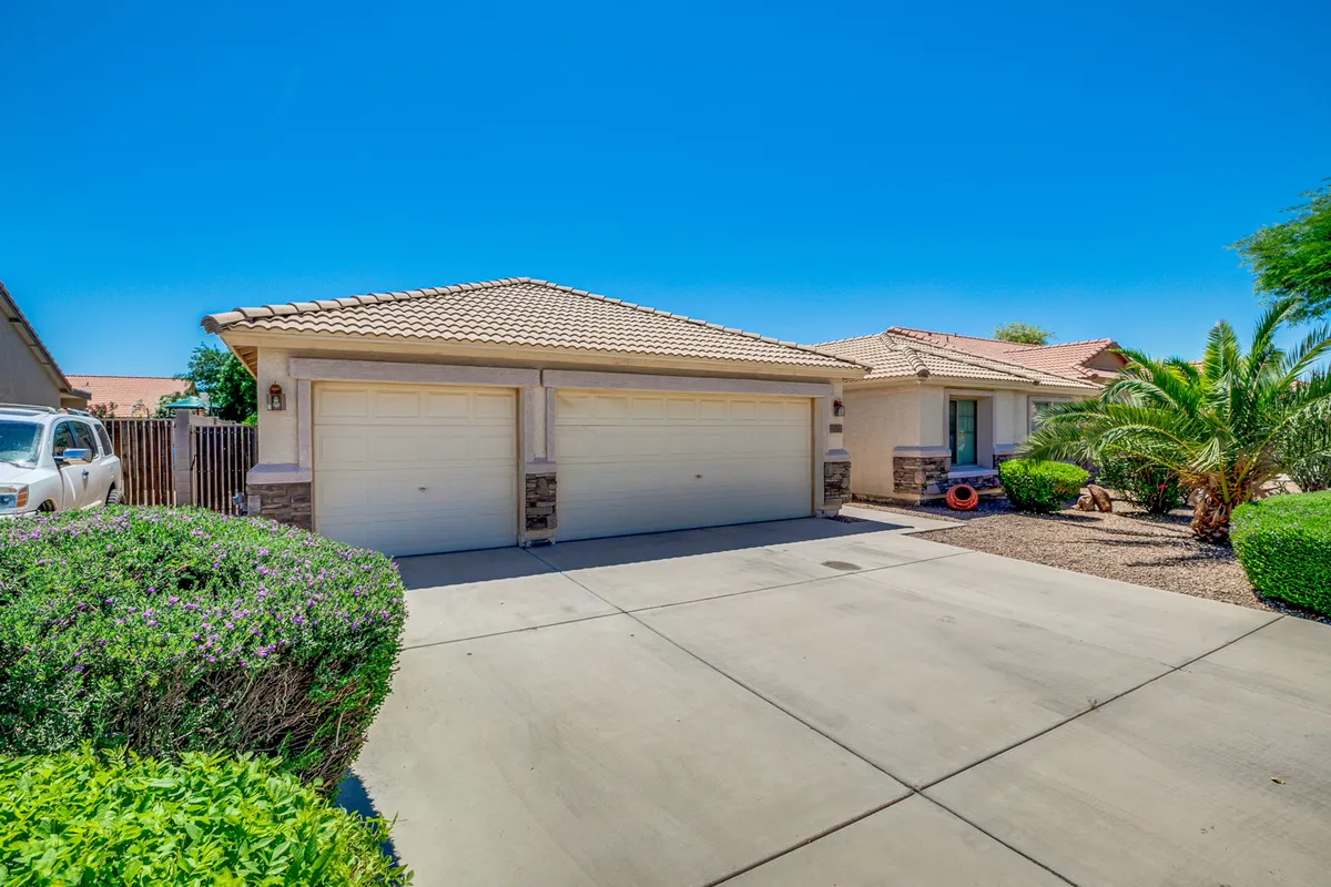 The front view of the home, featuring a two-car garage, a landscaped front yard with palm trees, and a welcoming sidewalk. The setting is bright and inviting, hinting at the family-friendly neighborhood and curb appeal.
