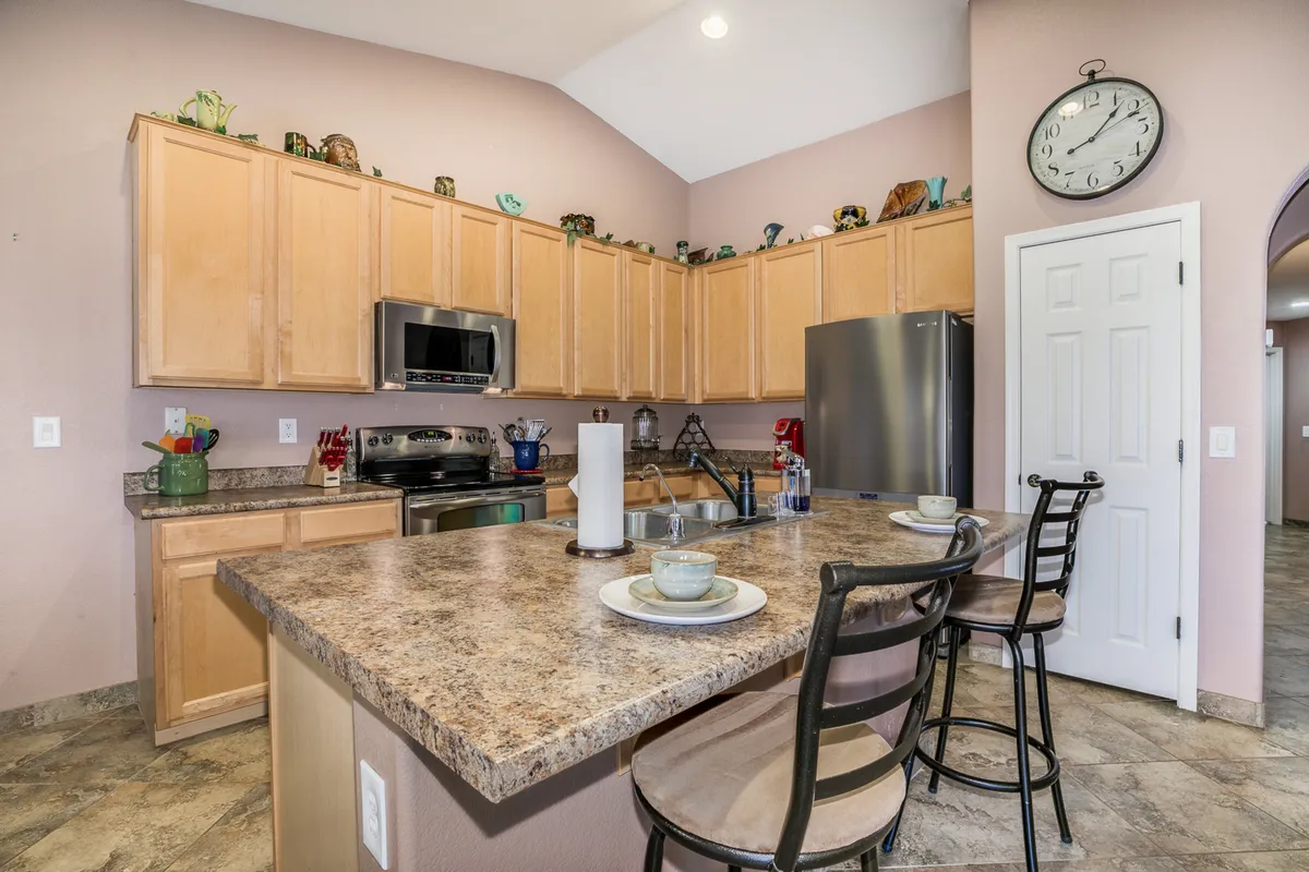 A view of a well-appointed kitchen featuring a central island, stainless steel appliances, and colorful decor accents. The space feels bright, cheerful, and designed for both cooking and socializing—ideal for family meal preparation and conversation. The kitchen flows naturally into the rest of the living area, reinforcing the open-concept narrative.