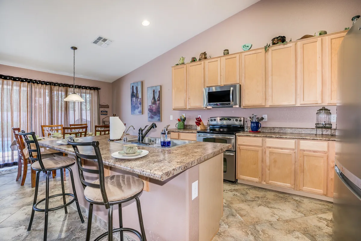 This interior shot features a modern kitchen island with stainless steel appliances and a visible dining area, suggesting ample space for cooking and entertaining. Decorative wall art and warm lighting add a welcoming touch, supporting the narrative of group meals and shared culinary adventures.