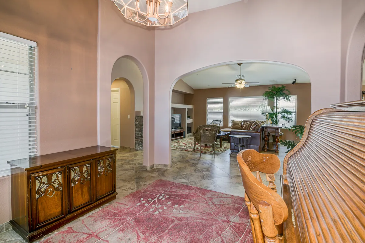 This image captures a bright, open living area anchored by a chandelier and wooden sideboard, with arched doorways leading to a comfortable lounge space. The arrangement is clearly designed for gatherings, whether for movie nights or casual conversations after a day of adventure.