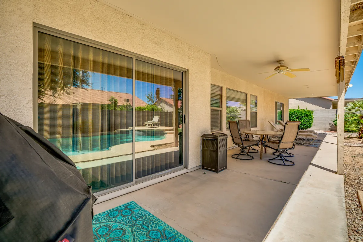 This exterior image captures the tranquil backyard featuring a sparkling swimming pool with patio furniture arranged for relaxing and socializing. The sliding glass door hints at easy indoor-outdoor flow, and the scene invites guests to imagine lounging by the pool on sunny Arizona days or gathering for evening barbecues.